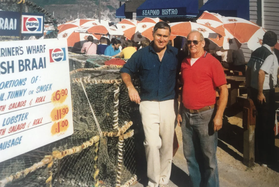 An archive photo from the early days of the Wharf, beside a hand-painted fish braai price board