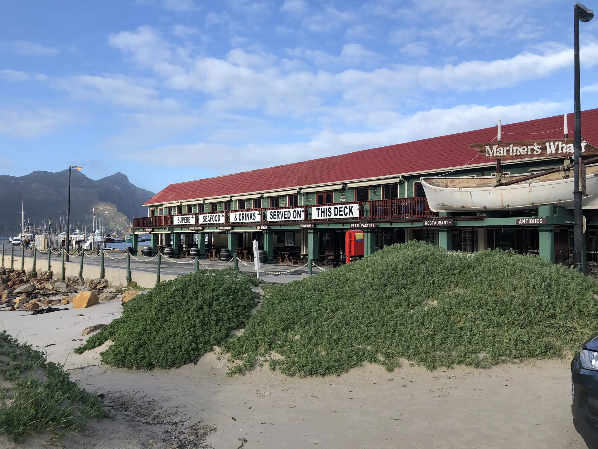 Mariner’s Wharf’s red roof and lifeboat at the end of Hout Bay beach
